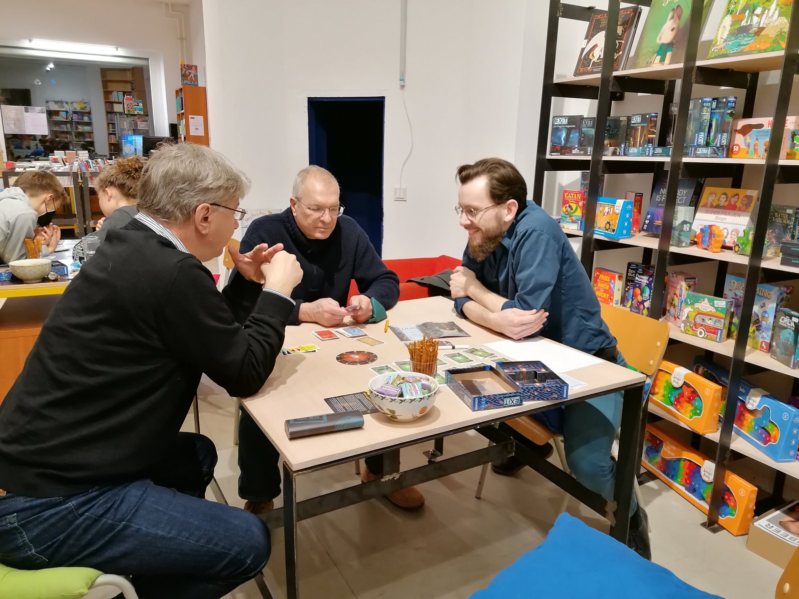 Tucholsky-Buchhandlung: Buchhändler Jörg Braunsdorf (Foto Mitte) hat seine Kunden zu einem Spieleabend in die Buchhandlung eingeladen. In kleineren Gruppen wurde, abgesichert durch 2G+, ein „Exit“-Spiel von Kosmos gespielt. www.buchhandlung-tucholsky.de (Foto: Buchhandlung Tucholsky)