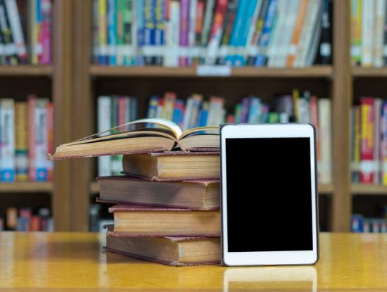 Tablet und Bücher in einer Bibliothek