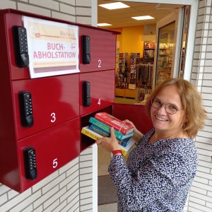 Helen Schirrmeister hat neben der Eingangstür zur ihrer Buchhandlung Schirrmeister eine Abholstation angebracht. Das Modell „Panko“ der Firma Max Knobloch erstrahlt im zum Buchhandlungs-Logo passenden Rot. Kunden können bei der Bestellung angeben, dass sie ihre bestellte Ware in die Abholstation gelegt bekommen wollen. Mithilfe eines vierstelligen Codes kann dann jederzeit abgeholt werden. (Foto: Buchhandlung Schirrmeister)